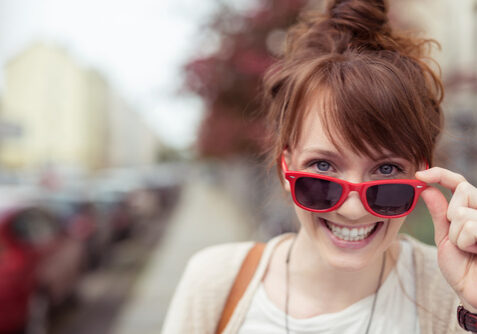 frau schaut lachend ber ihre rote sonnenbrille